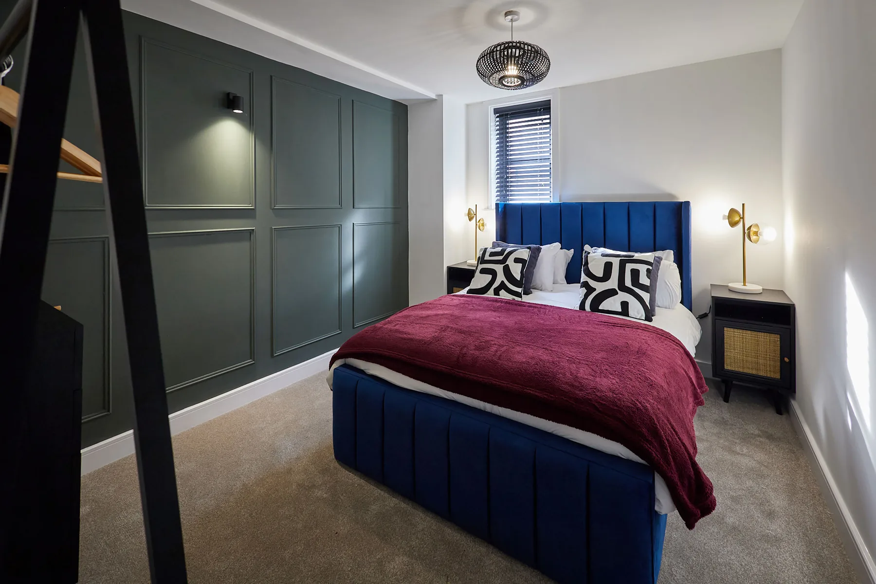 A bedroom with a bed dressed in burgundy bedding and dark blue upholstery.