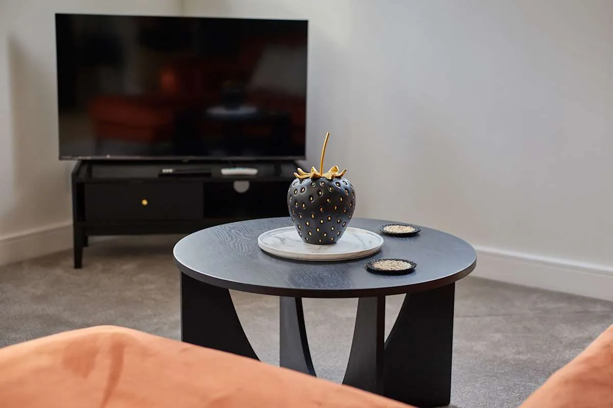 Una sala de estar con un televisor y una mesa de centro redonda.
