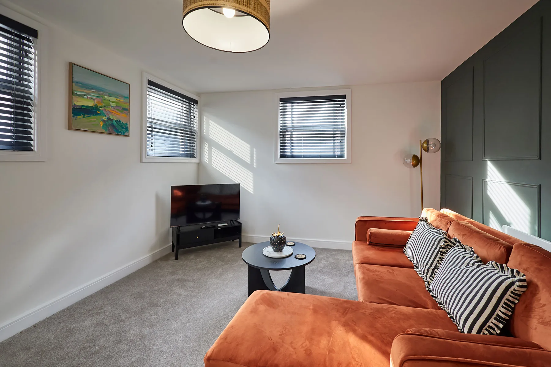 A living room with an orange sectional, television, and coffee table.