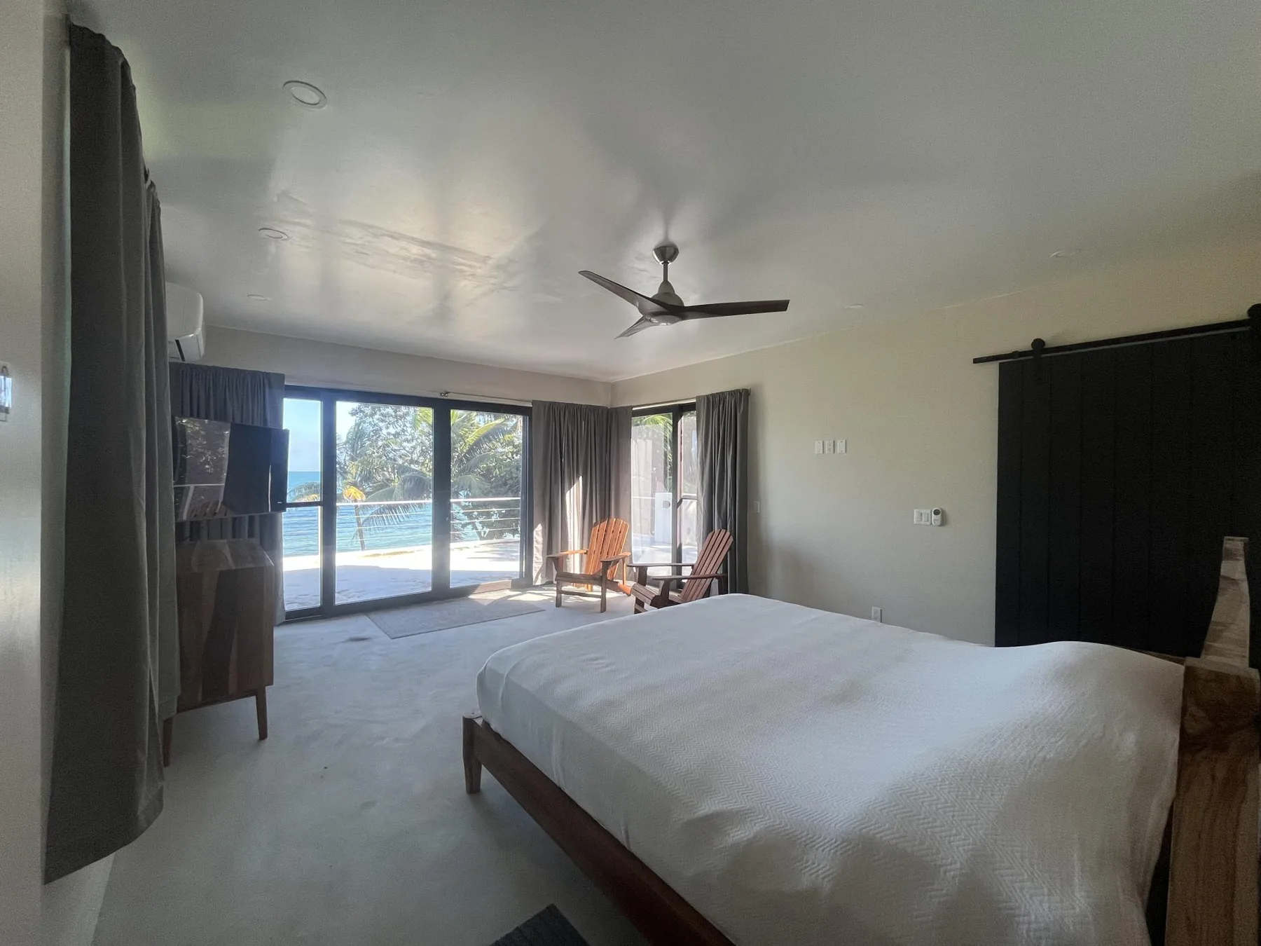 A bedroom with a bed, seating, and sliding glass doors opening onto a patio.