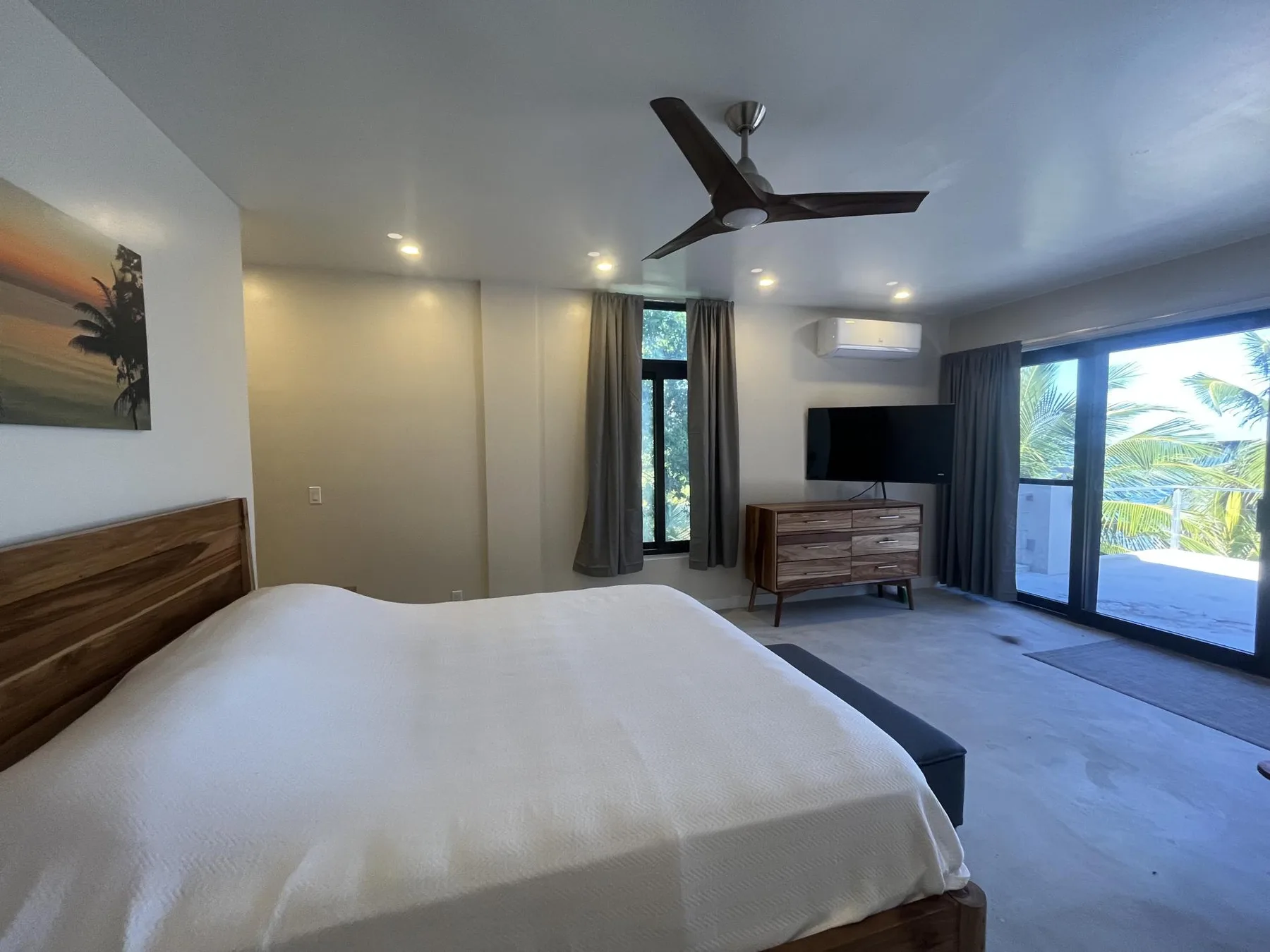 A bedroom with a bed, dresser, and sliding glass doors opening to a patio.