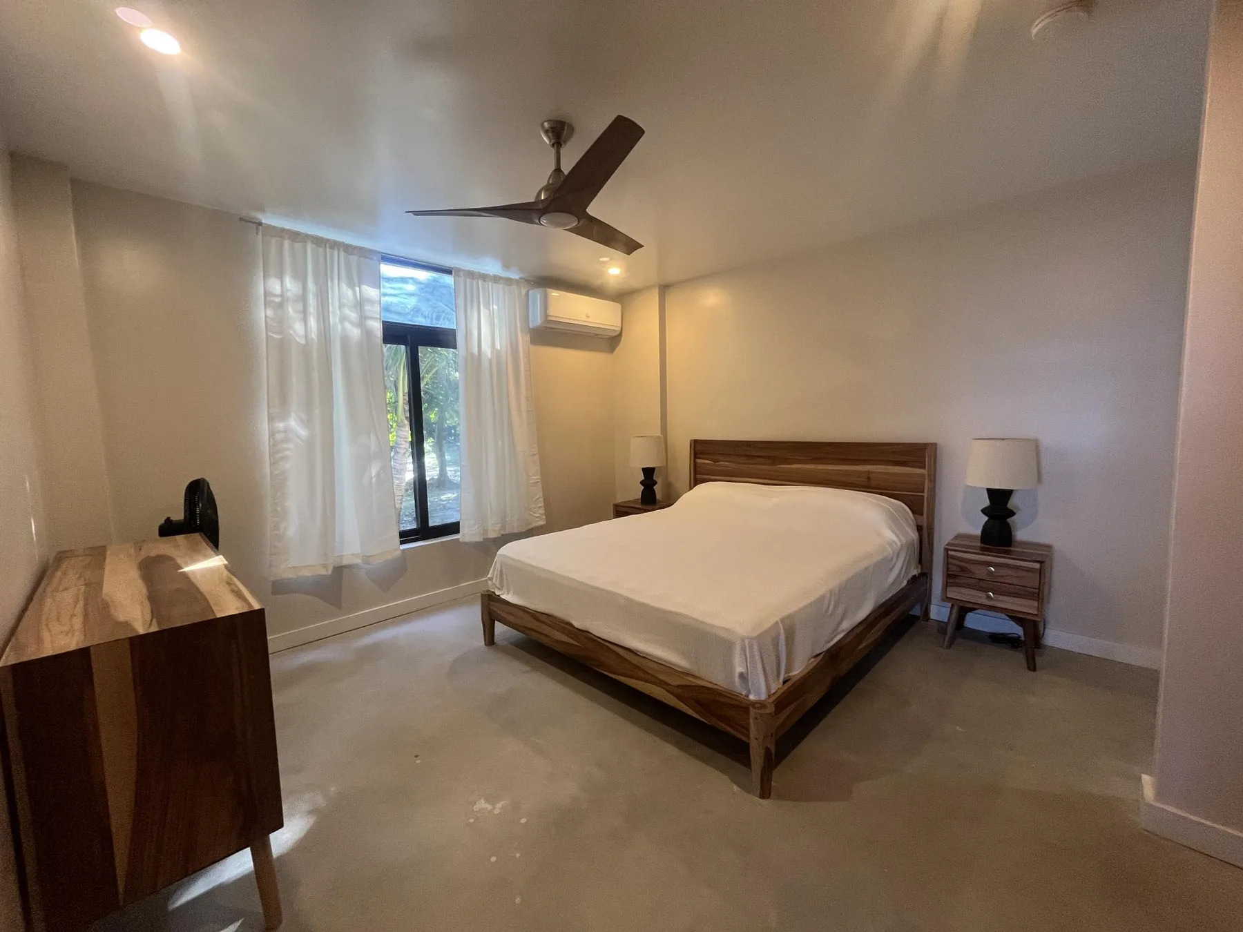 A bedroom with a wooden bed, bedside tables, and a window with curtains.