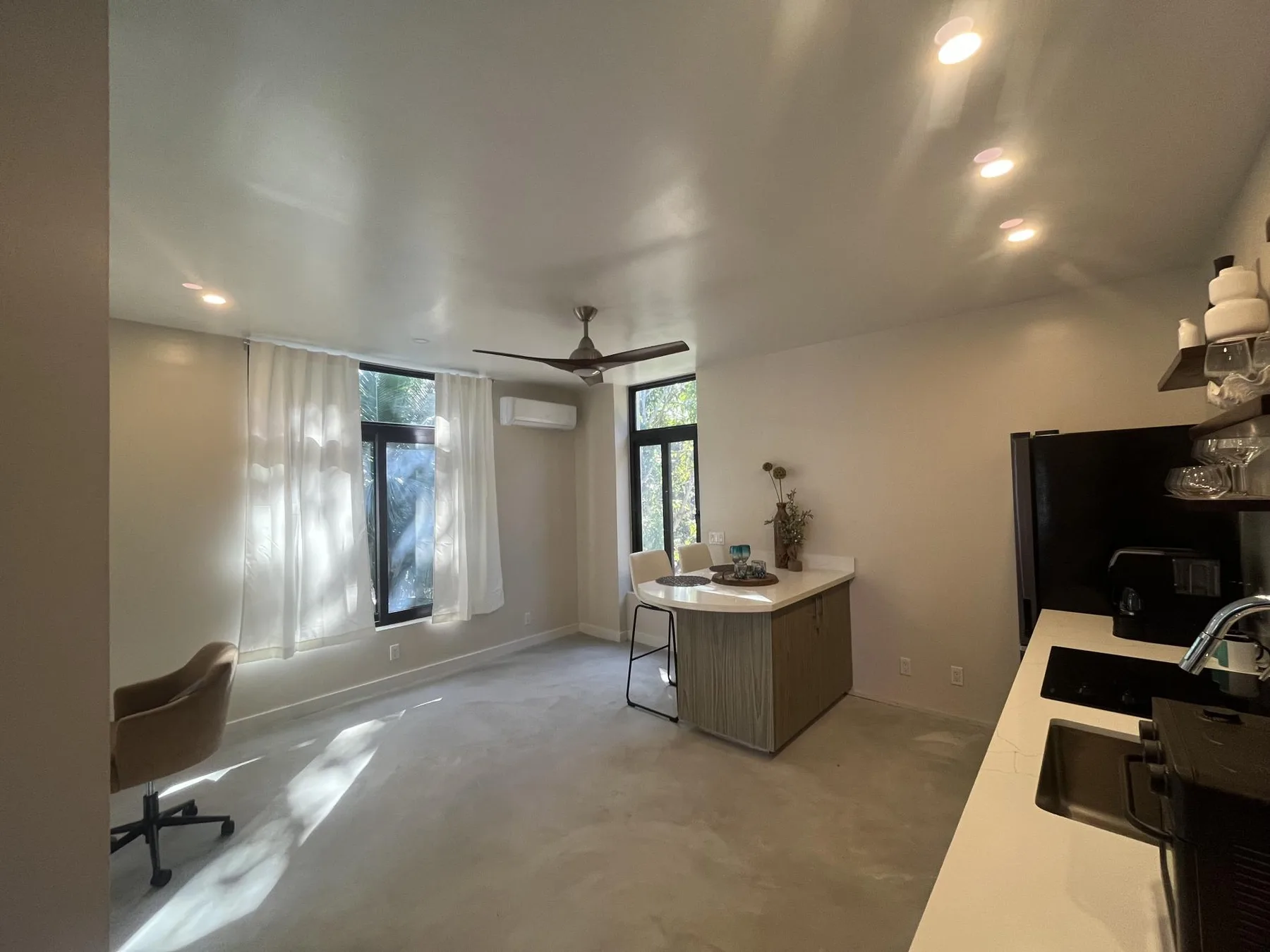 An open kitchen and living area with a counter and large windows.