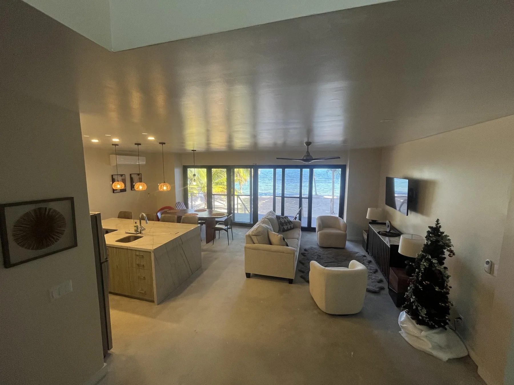 A bright living room opens onto large windows overlooking the water.