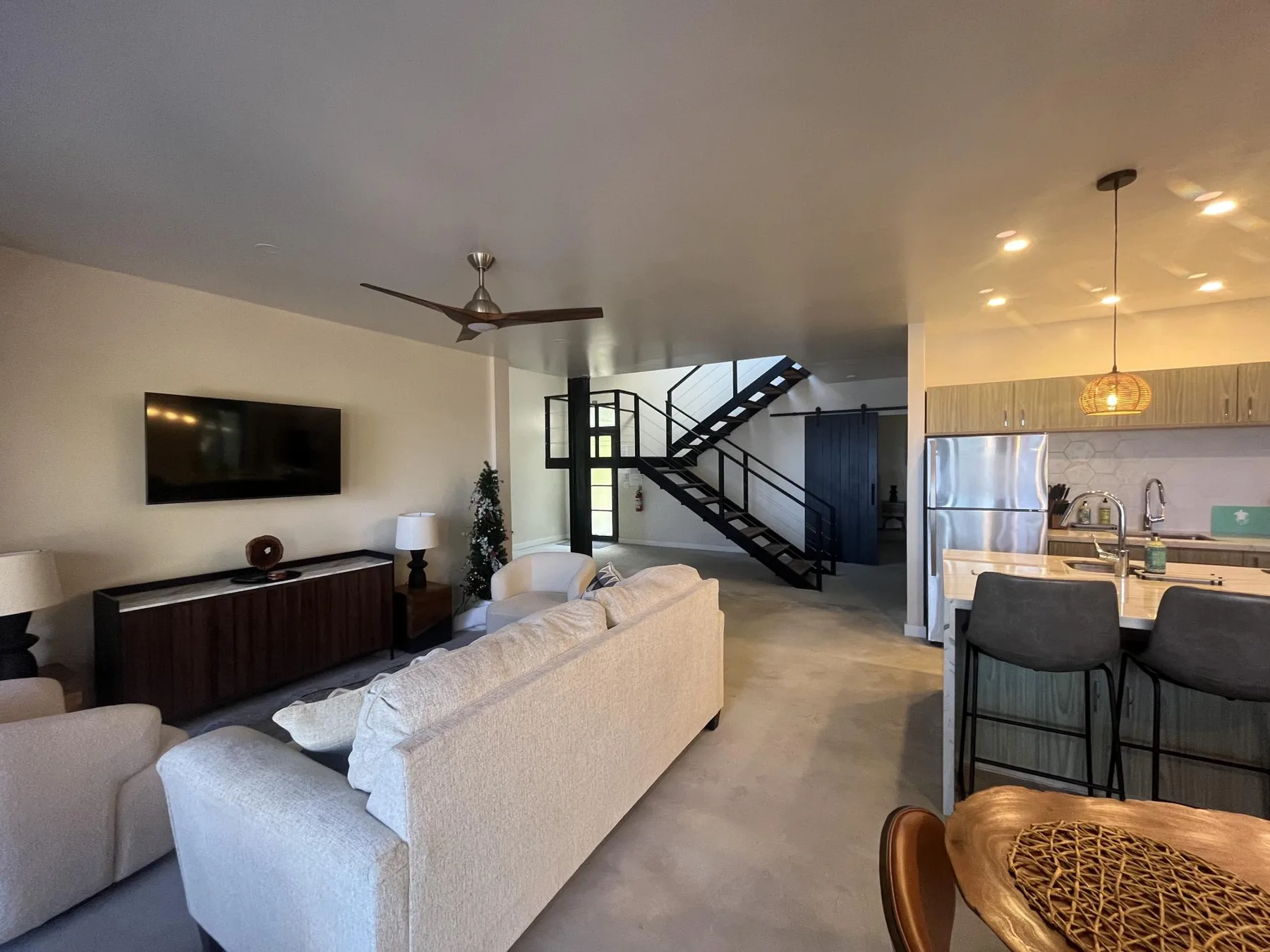 An open-plan living room and kitchen with a staircase and counter seating.