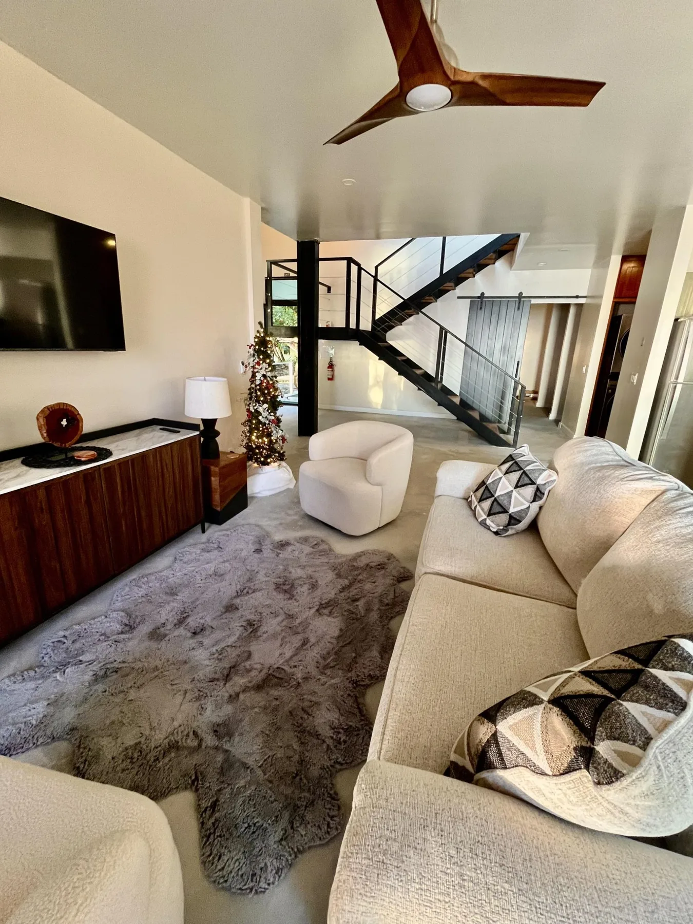 A living room with seating, a television, and a staircase.