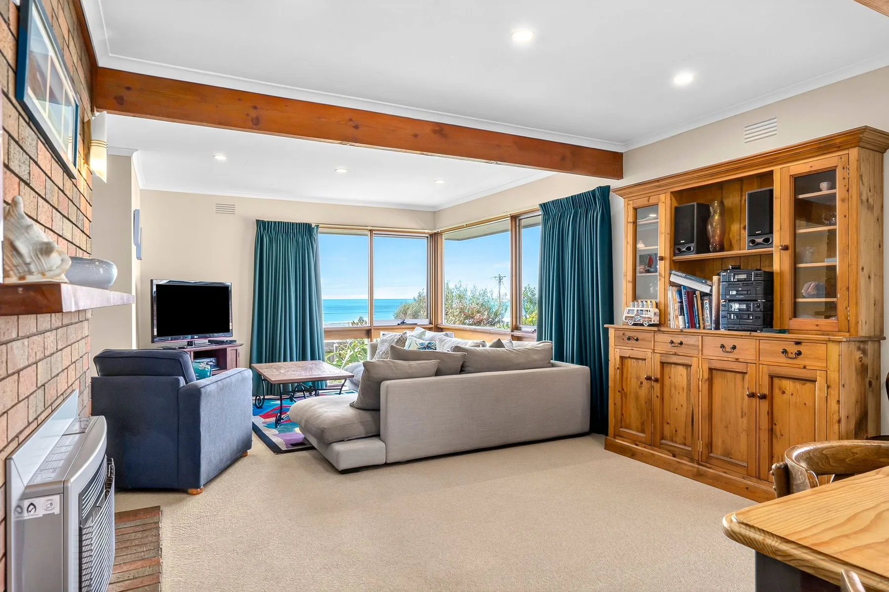 Una sala de estar con asientos, un mueble de madera y ventanas con vista al océano.