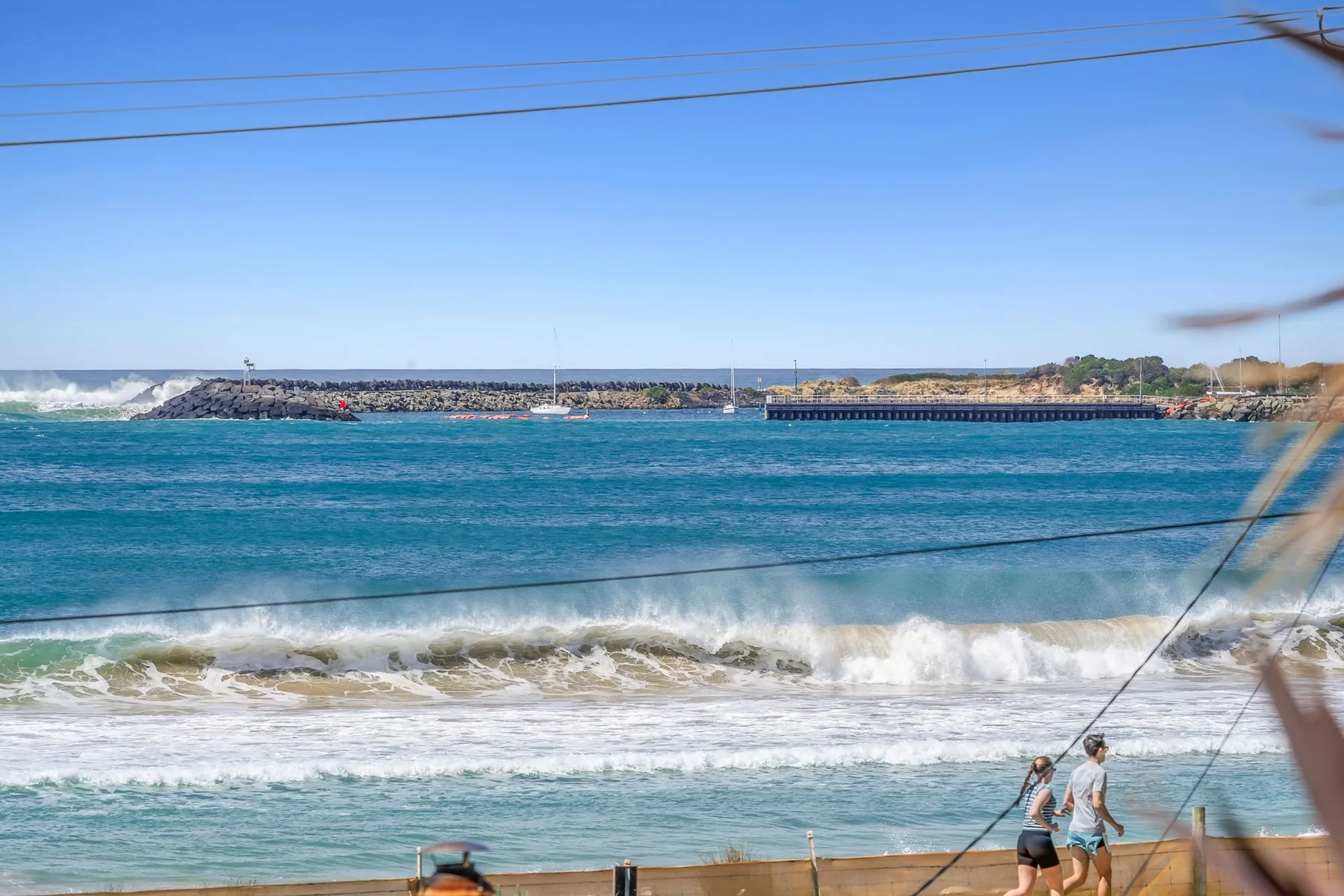 Un paisaje costero con agua turquesa, olas rompientes y una costa lejana.