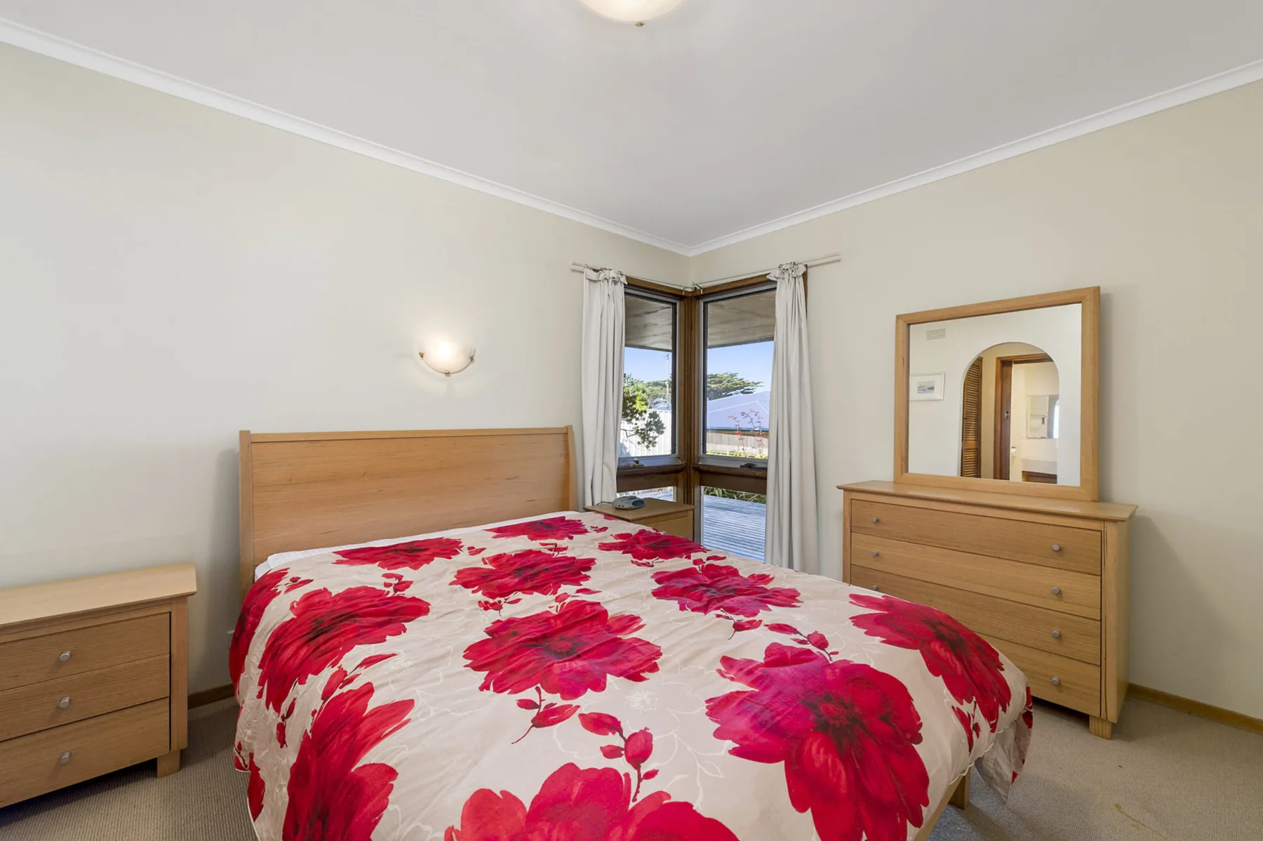 Un dormitorio con una cama cubierta con una llamativa colcha floral roja.