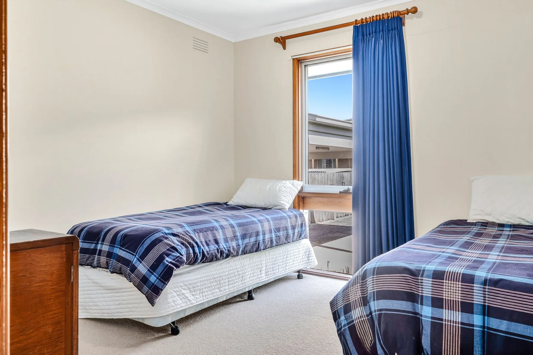 Un dormitorio con dos camas individuales vestidas con ropa de cama azul a cuadros.