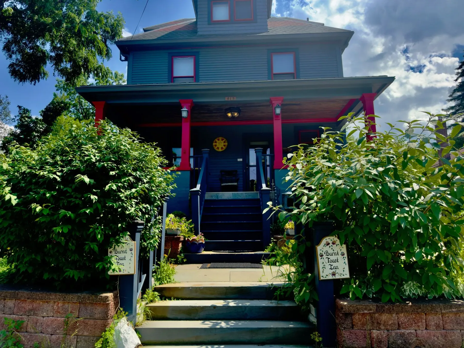A blue house with a red porch and stairs