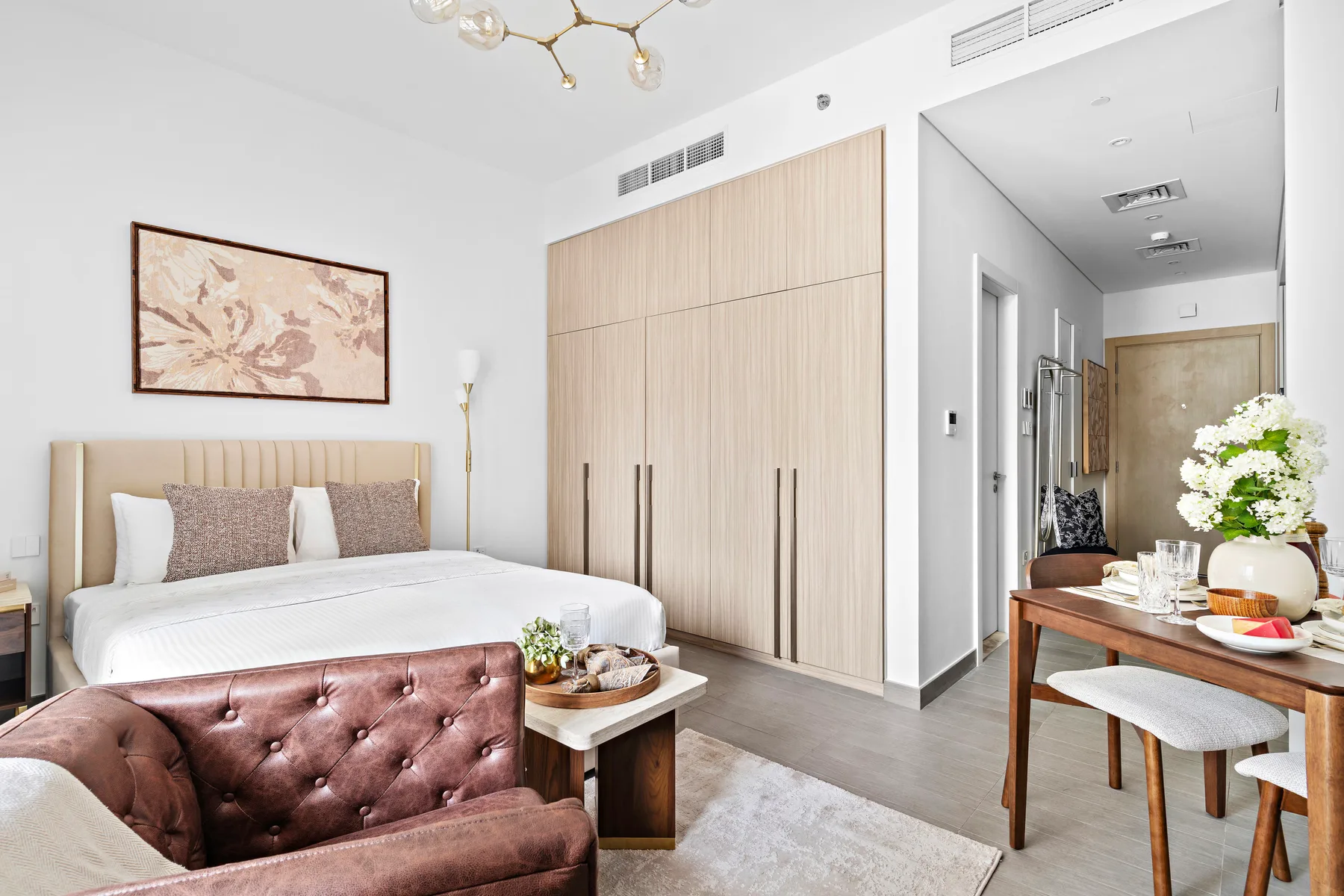 Un dormitorio luminoso con una cama, una zona de asiento acolchada y una mesa de comedor.