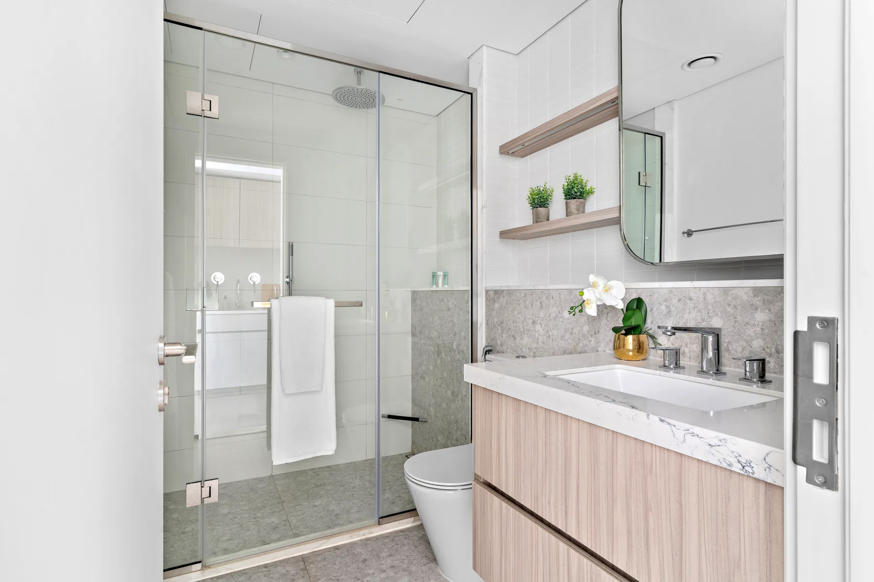 Un baño luminoso con una ducha de vidrio y un mueble con lavabo.