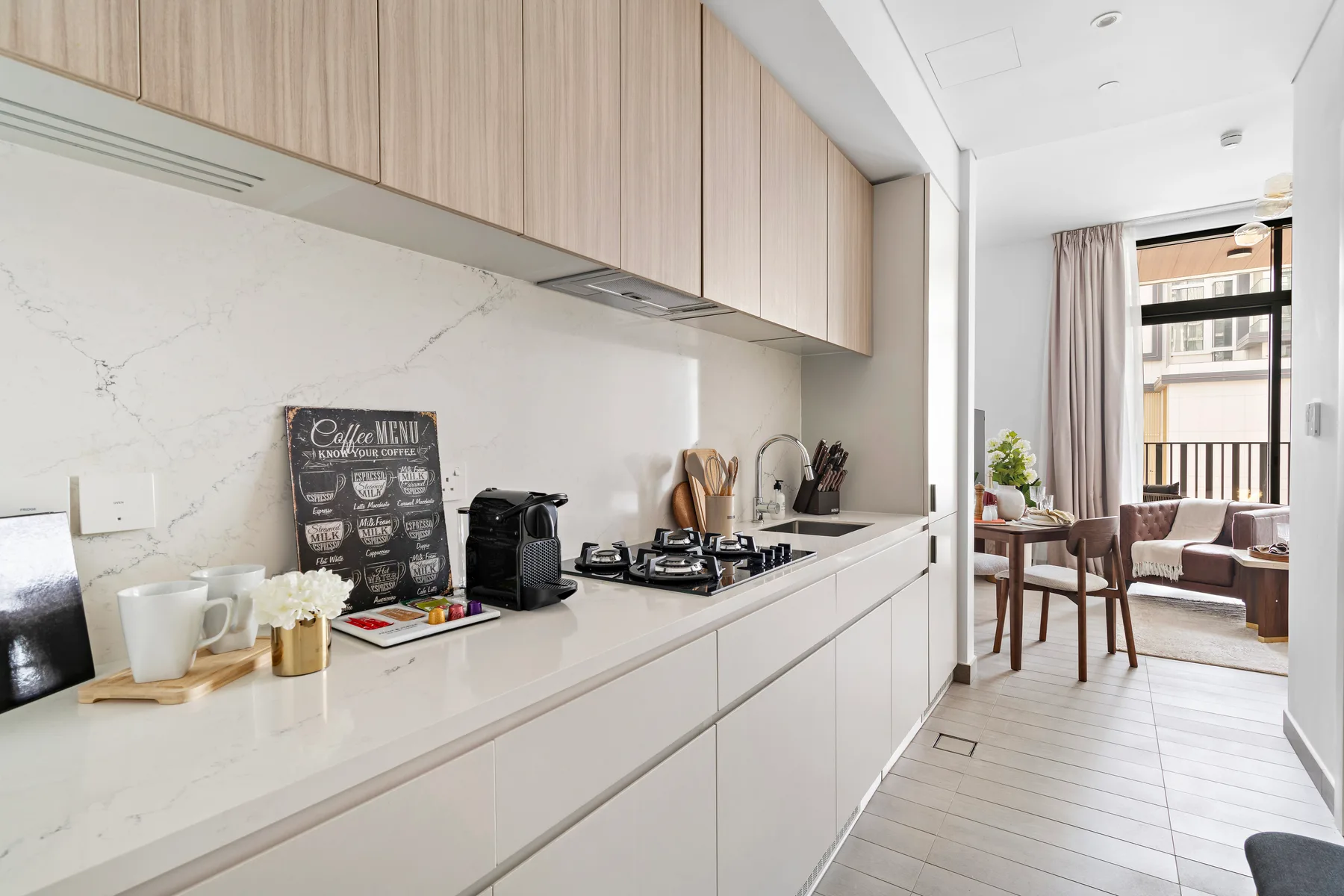 Una cocina luminosa con gabinetes claros y una encimera abierta a un comedor.