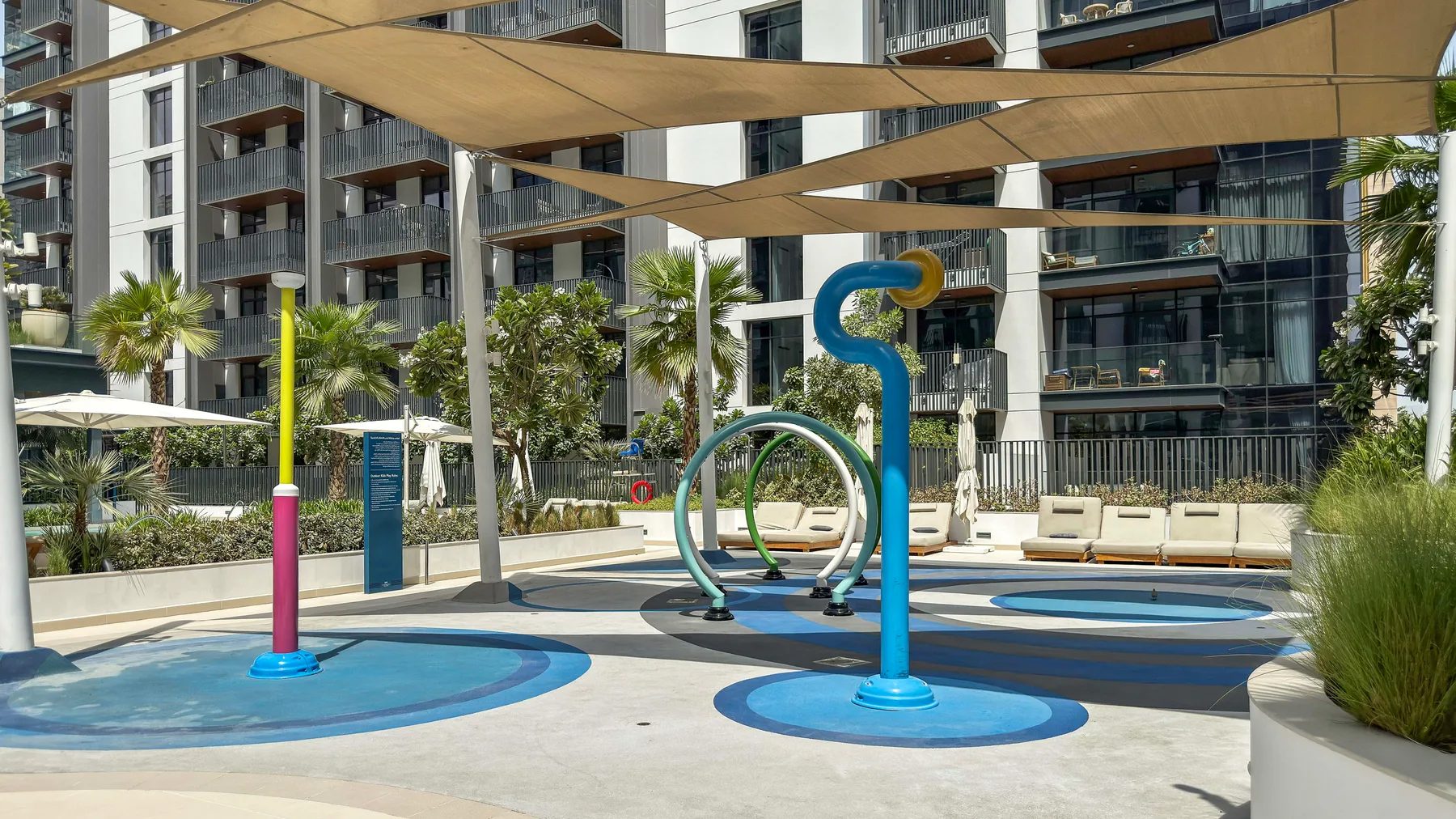 Una zona de juegos de agua al aire libre con estructuras coloridas bajo toldos.