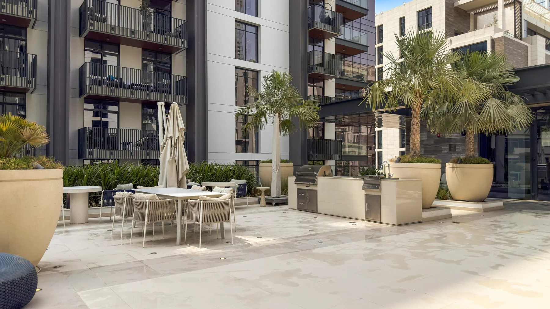 Un patio de un complejo de apartamentos con asientos al aire libre y palmeras en macetas.