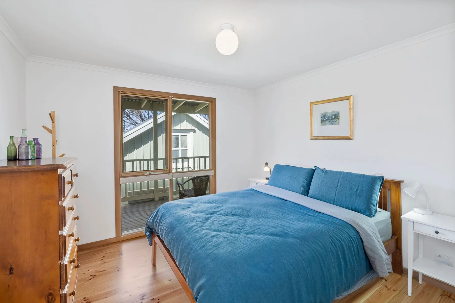 A bedroom with a bed covered in blue bedding and a glass door.