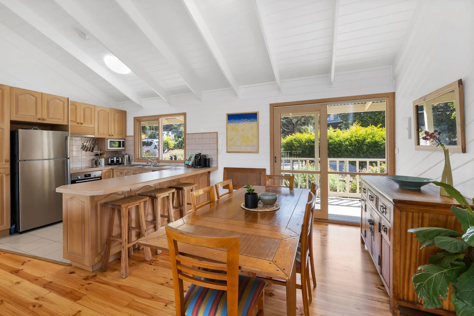 Una luminosa cocina y comedor con una mesa de madera e isla.
