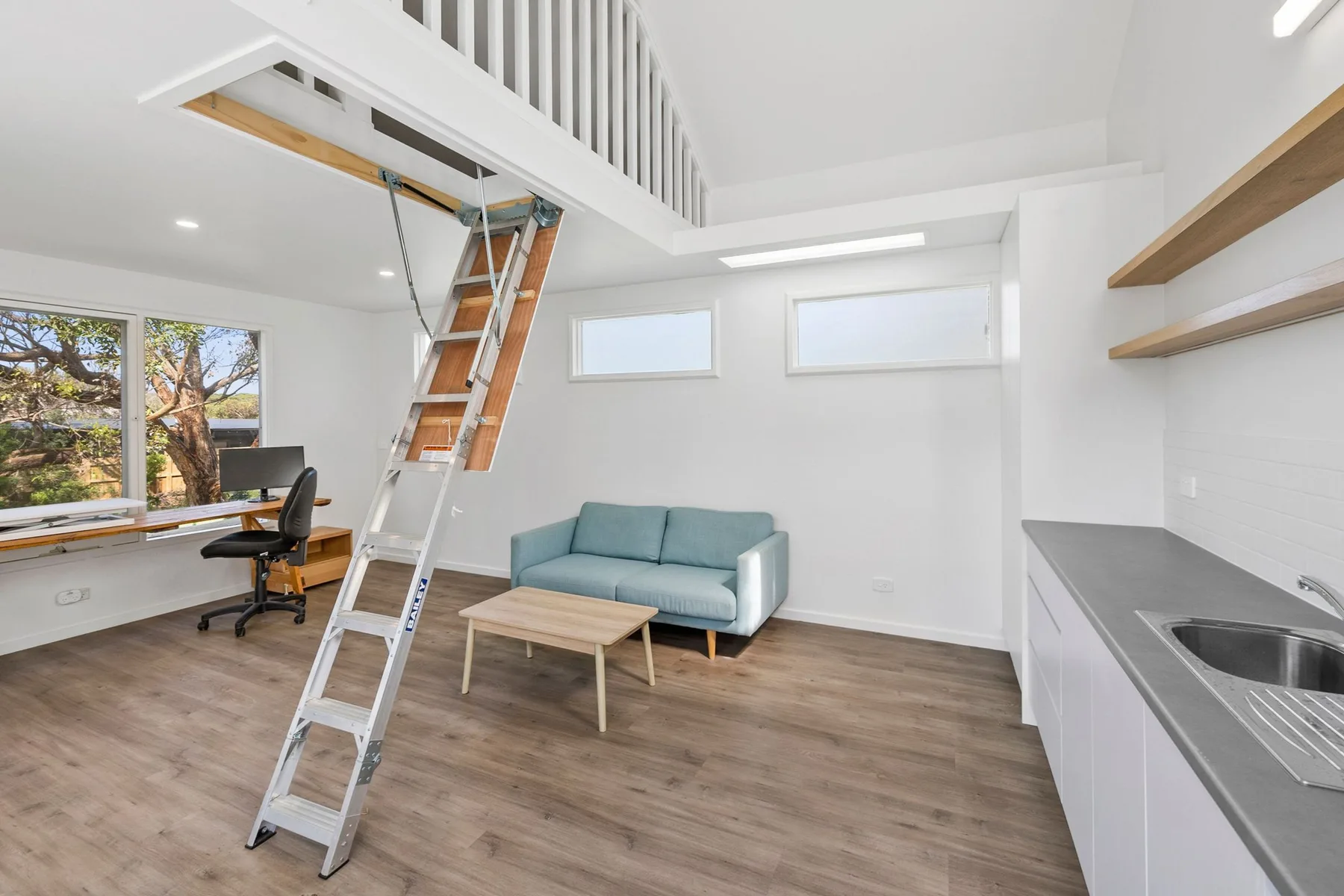 A bright open-plan room has a small seating area beside a kitchen counter.