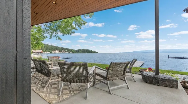 Un patio junto al lago con asientos al aire libre bajo un techo de madera.