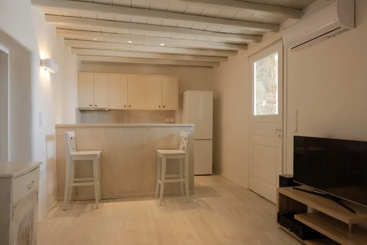 A bright open kitchen and living area with a breakfast counter and television.