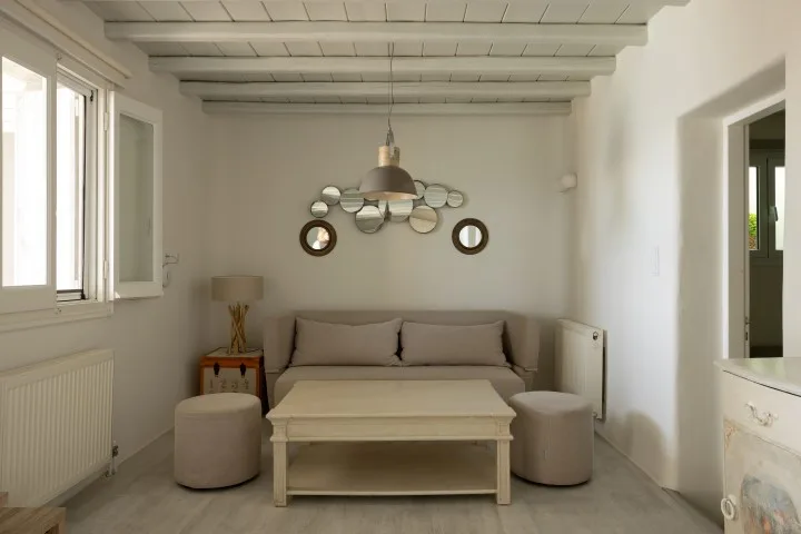 A living room with seating, a low table, and windows along the left wall.