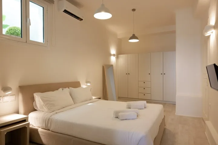 A bright bedroom with a neatly made bed and built-in wardrobes.