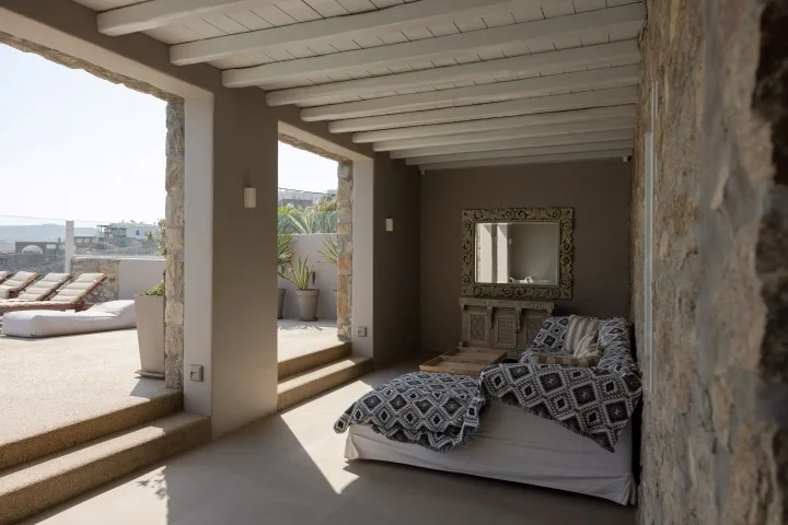 A covered outdoor lounge with cushioned seating and a low table.