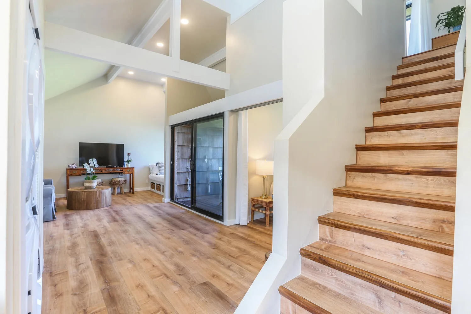 Una luminosa sala de estar abierta con suelo de madera y una escalera.