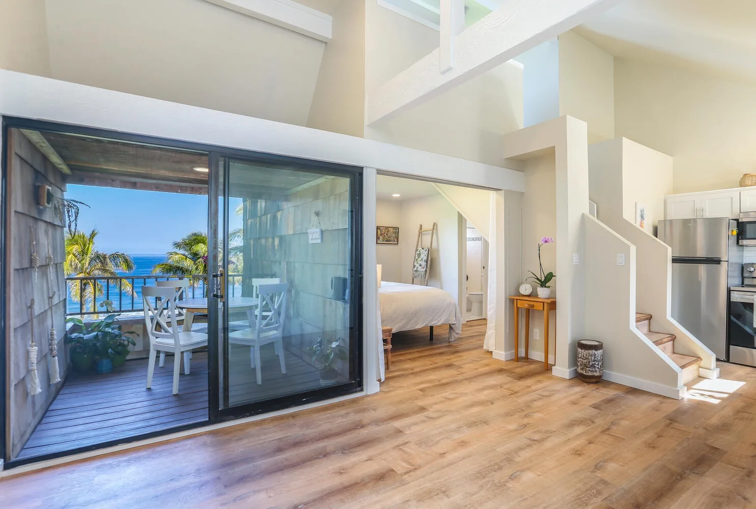 Una habitación luminosa y diáfana con puertas corredizas de vidrio, una cama y escaleras.