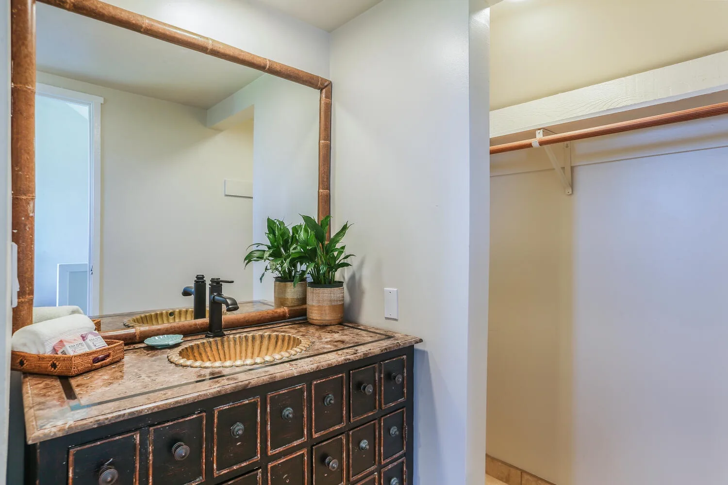 Un tocador de baño con lavabo y espejo está junto a un armario abierto.