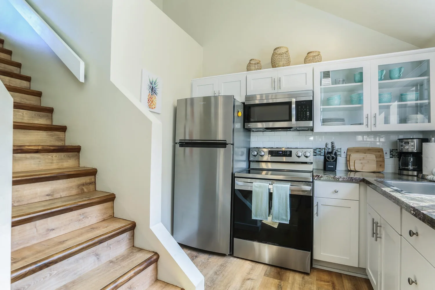 Una cocina luminosa con electrodomésticos de acero inoxidable y una escalera.