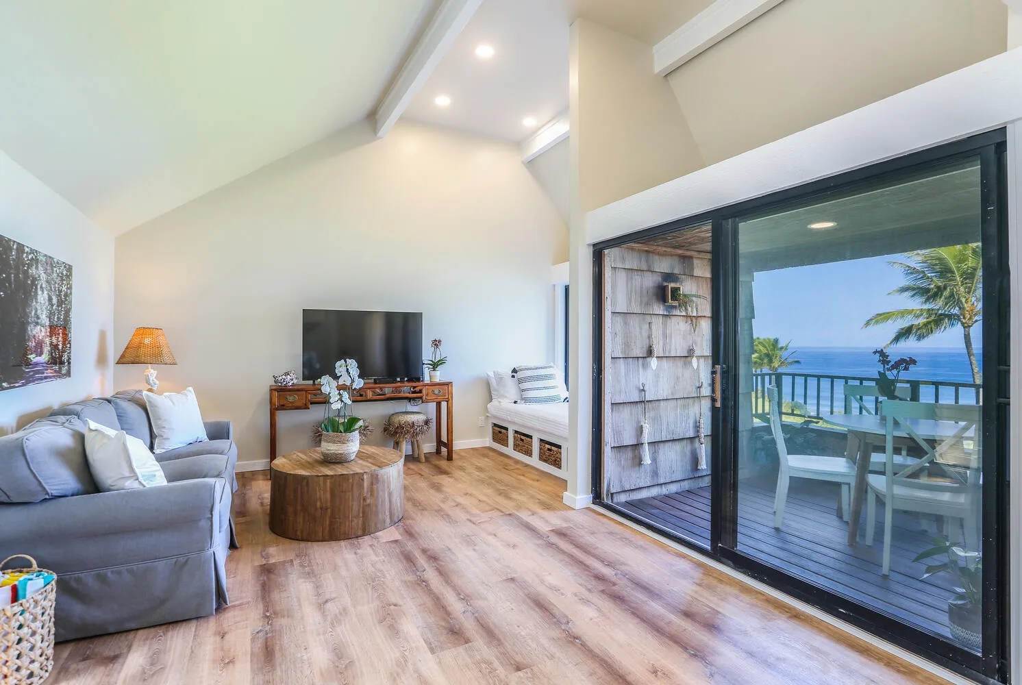 Una sala luminosa da a un balcón con vistas al mar.