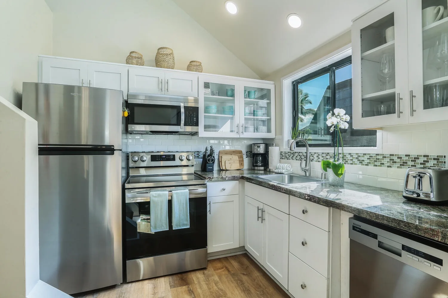 Una cocina luminosa con gabinetes blancos, electrodomésticos de acero inoxidable y una ventana grande.