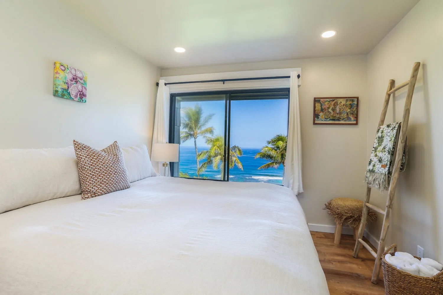 Un dormitorio luminoso con una cama grande frente a una ventana con vistas al mar.