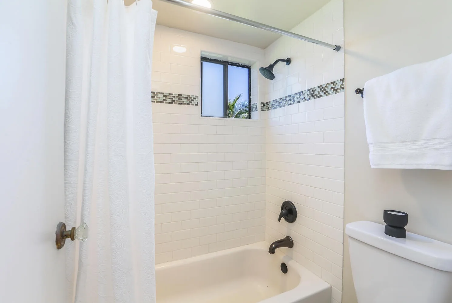 Un baño con azulejos, bañera, ducha y una ventana pequeña.