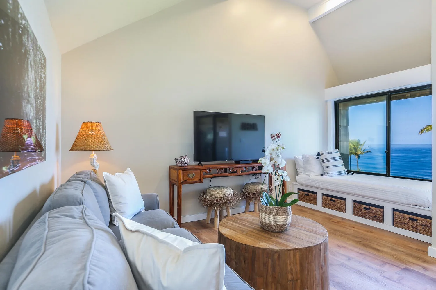 Una luminosa sala de estar con una zona de asientos y una gran ventana con vista al mar.