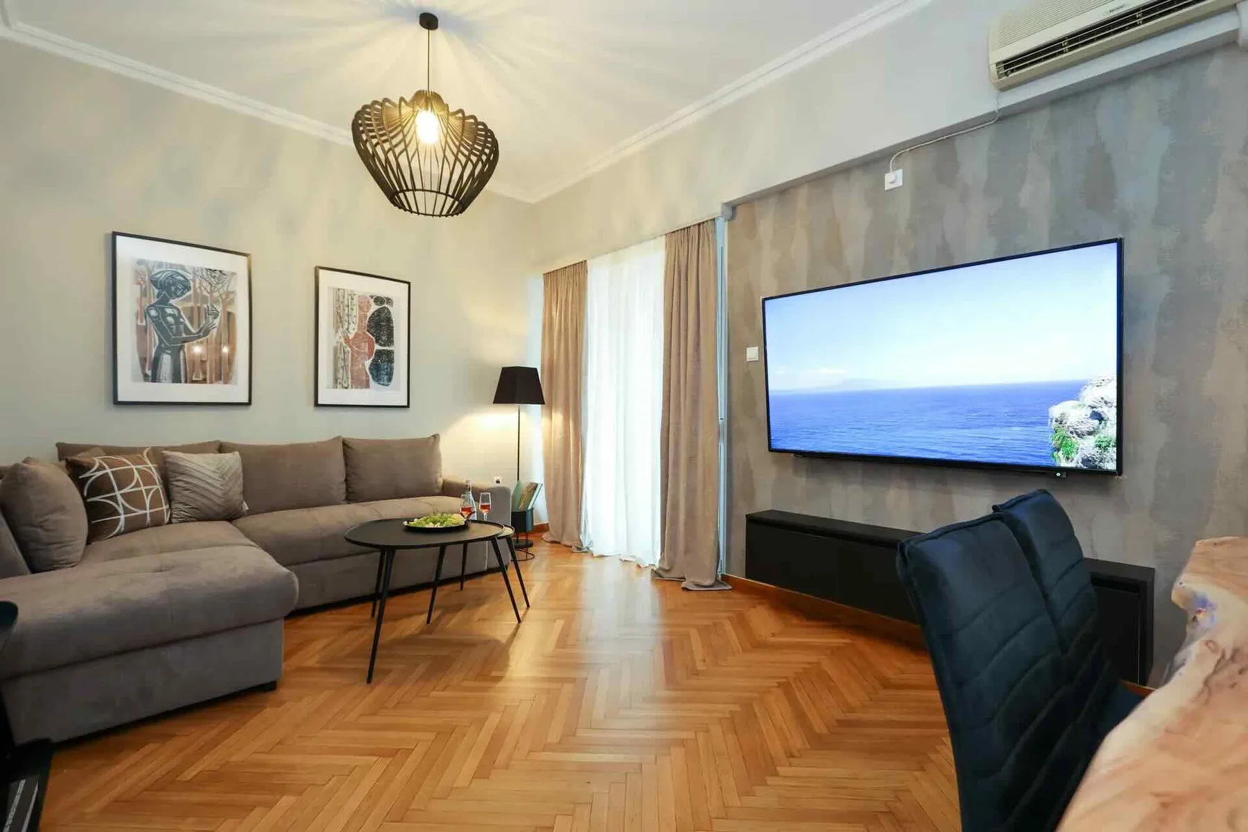 Una sala de estar con sofá, mesa de centro y televisor montado en la pared.