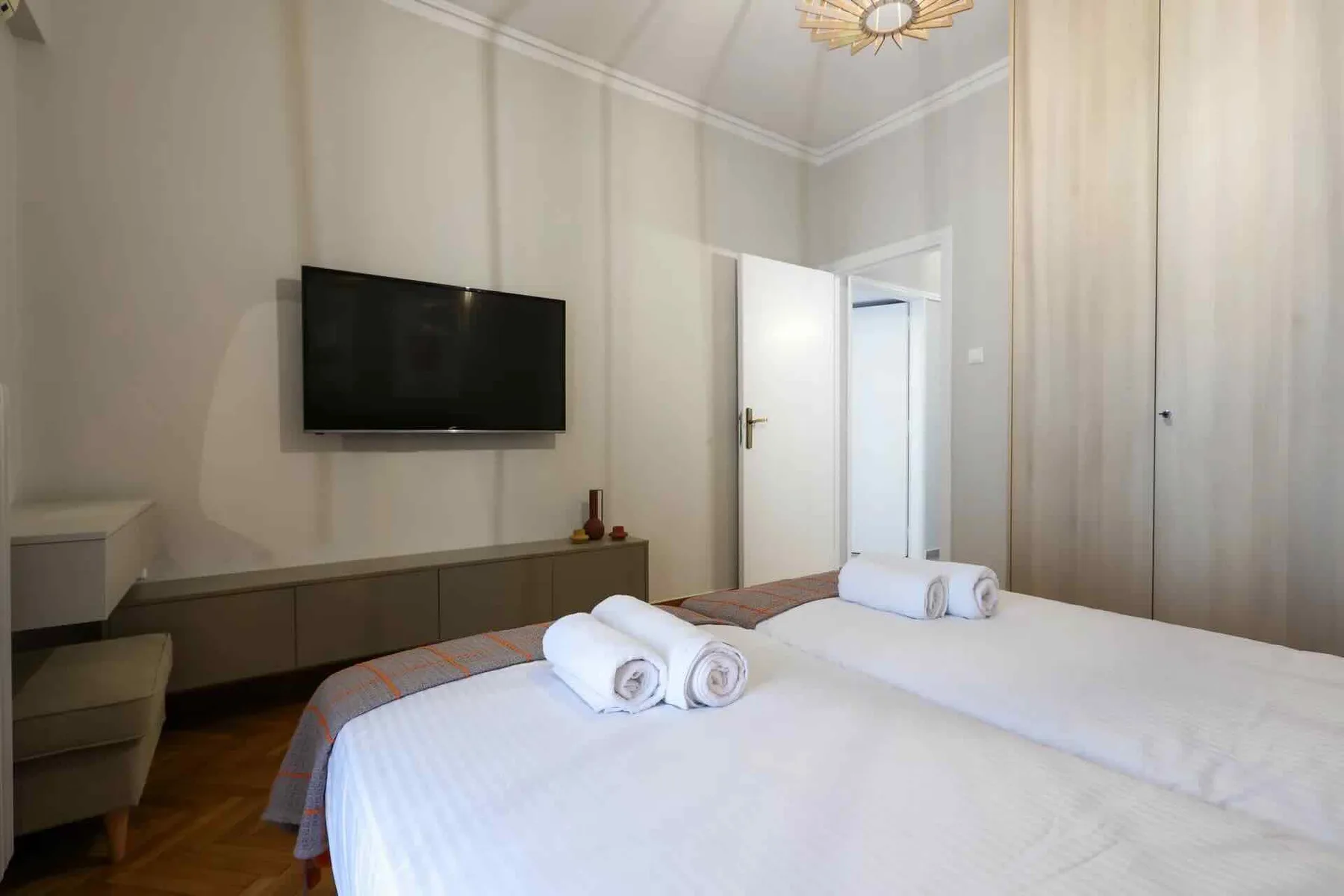 Un dormitorio con dos camas, toallas dobladas y un televisor montado en la pared.