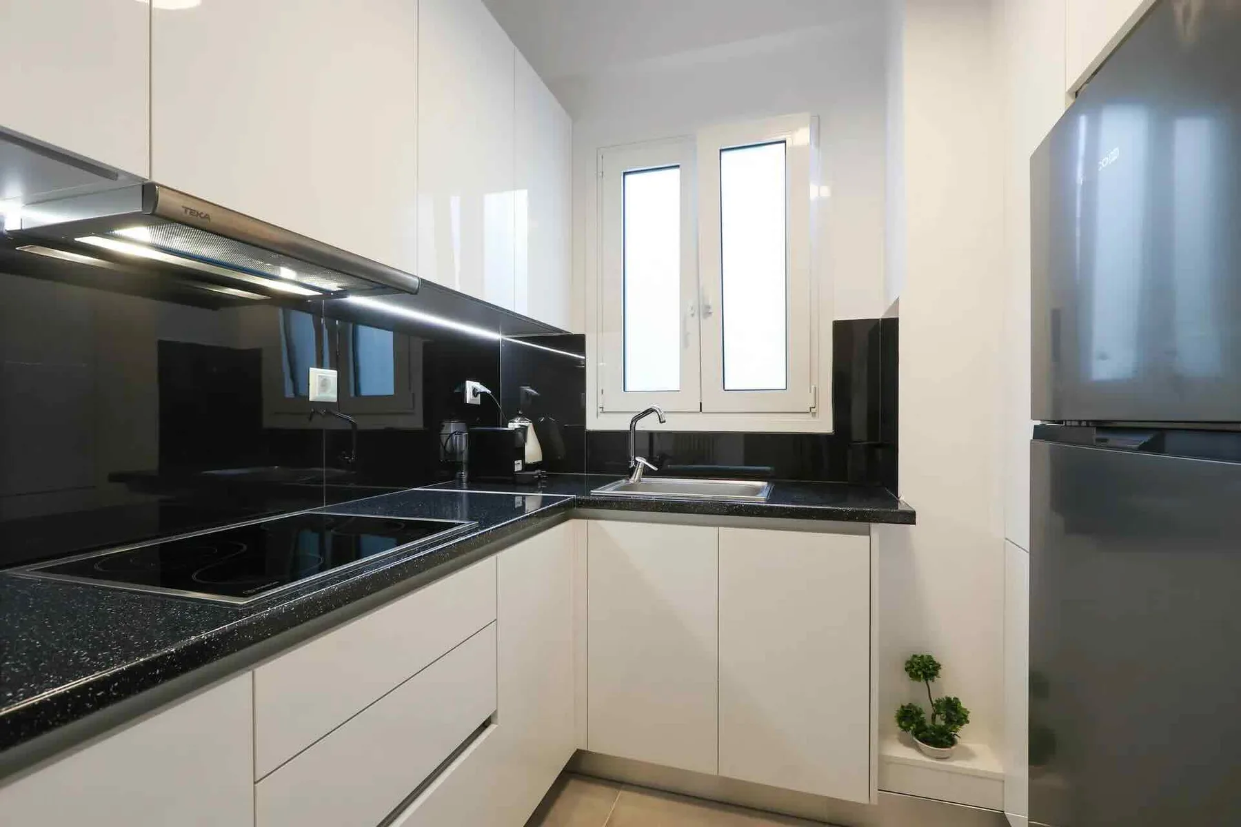 Una cocina moderna con encimeras oscuras y armarios blancos.