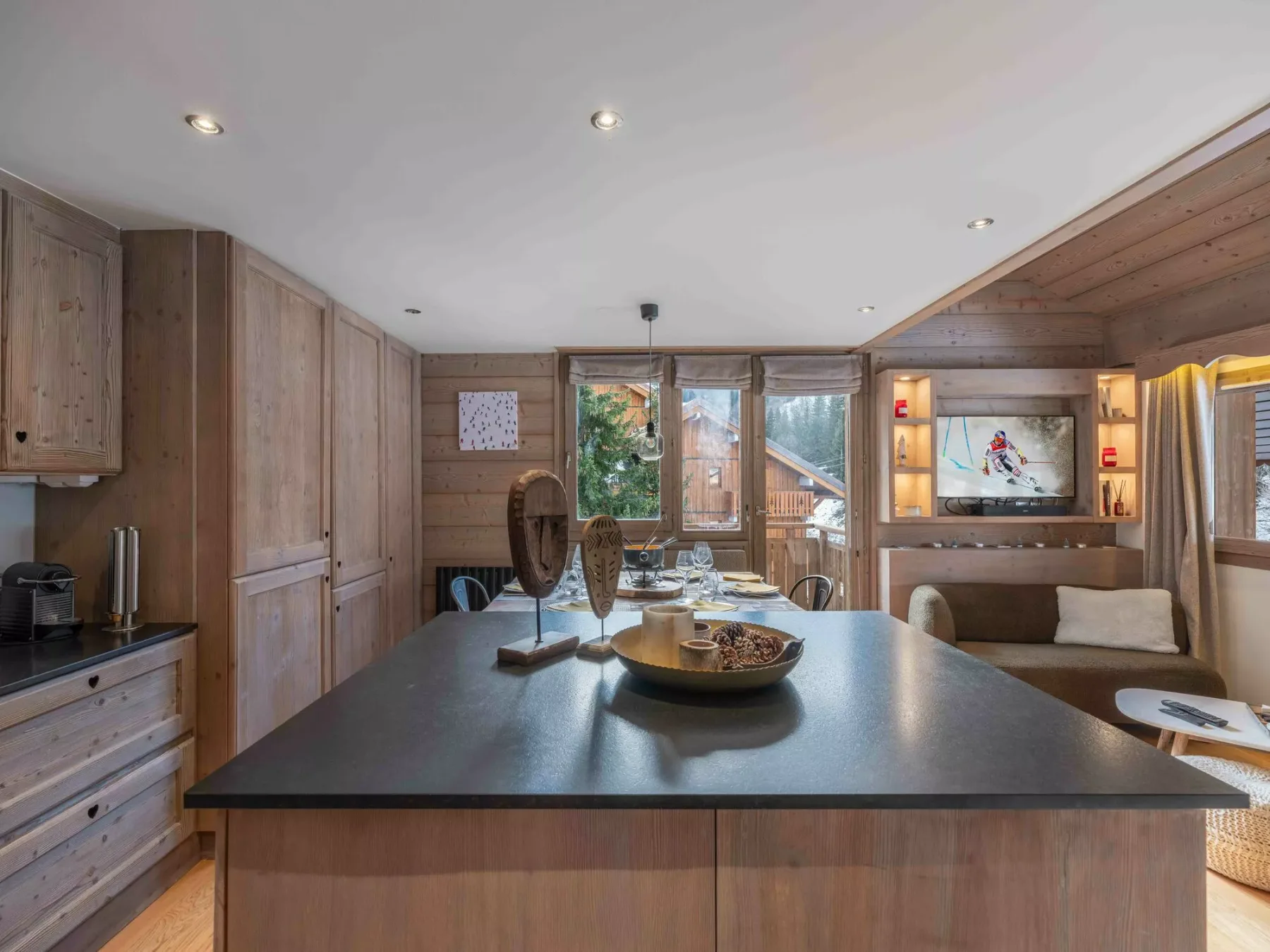 A wood-paneled kitchen and dining area with a large island and windows.