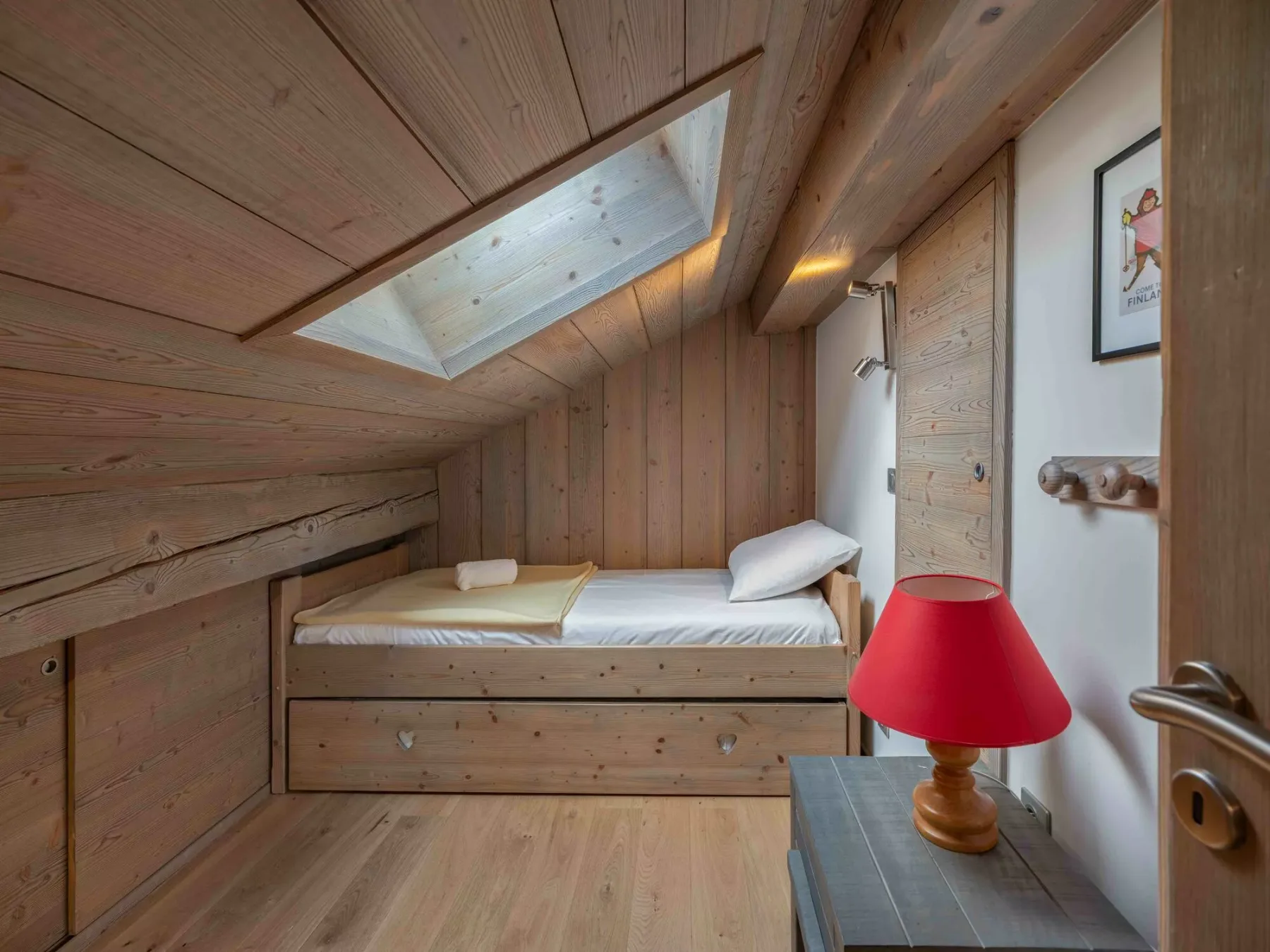 A wood-paneled bedroom with a bed beneath a skylight.