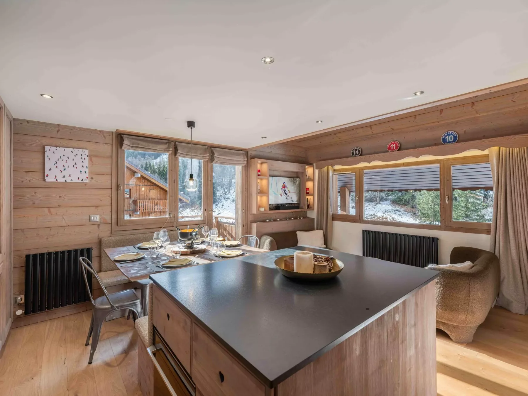 A wood-paneled dining area has a large table and windows overlooking snowy scenery.