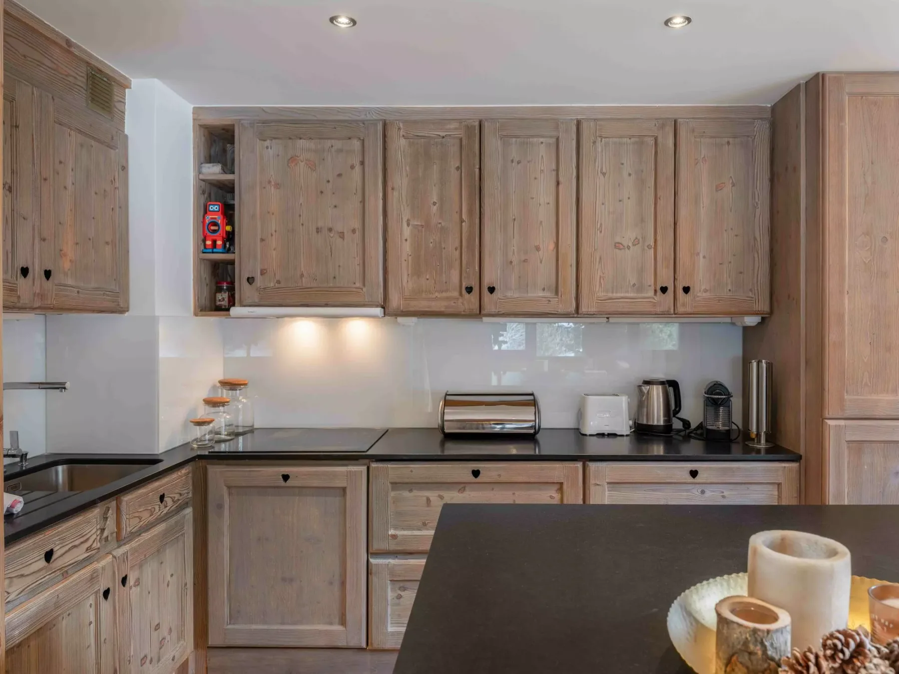 A kitchen with wooden cabinets, dark countertops, and a central island.