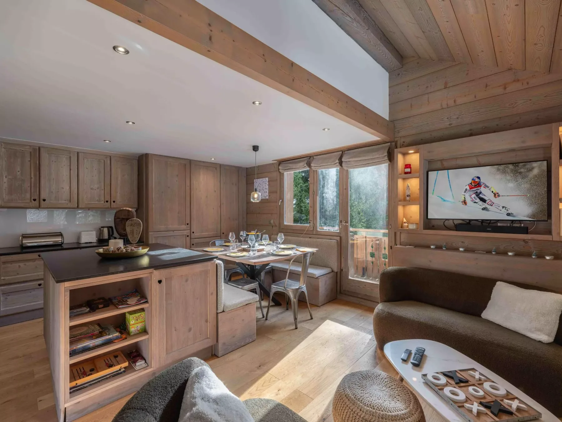 A wood-paneled living and dining area with a table beside large windows.