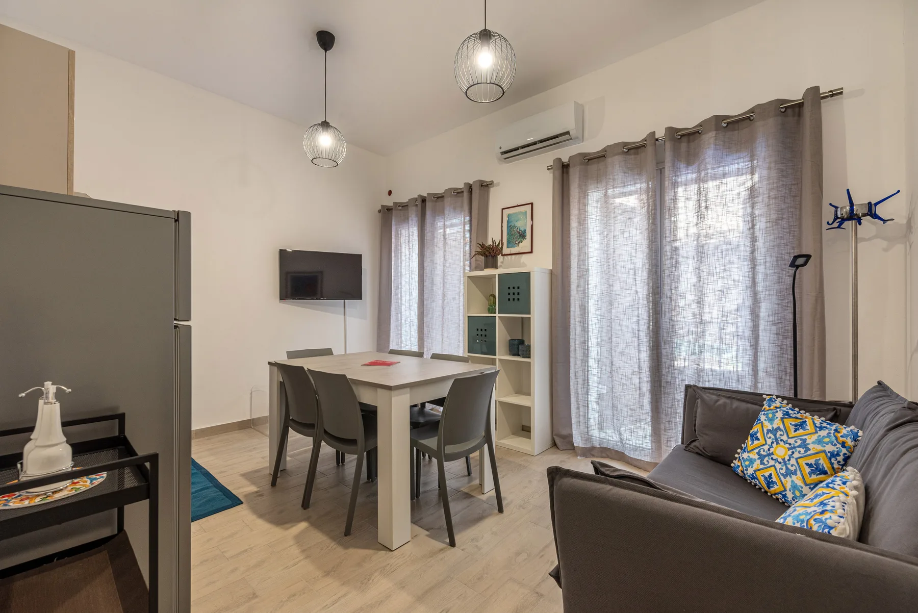 A dining and living room with a table, seating, and large curtained windows.