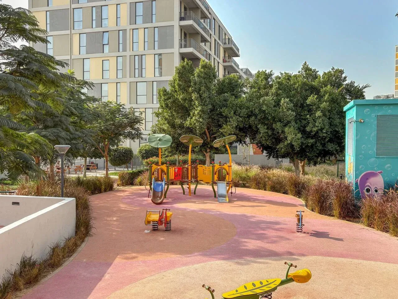 An outdoor playground with colorful play equipment among trees and buildings.