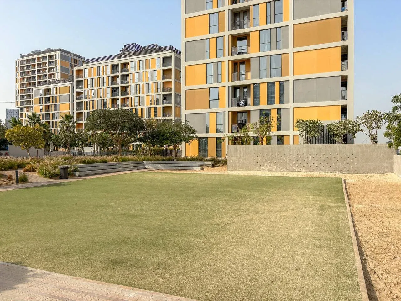 A landscaped courtyard lawn sits in front of modern apartment buildings.