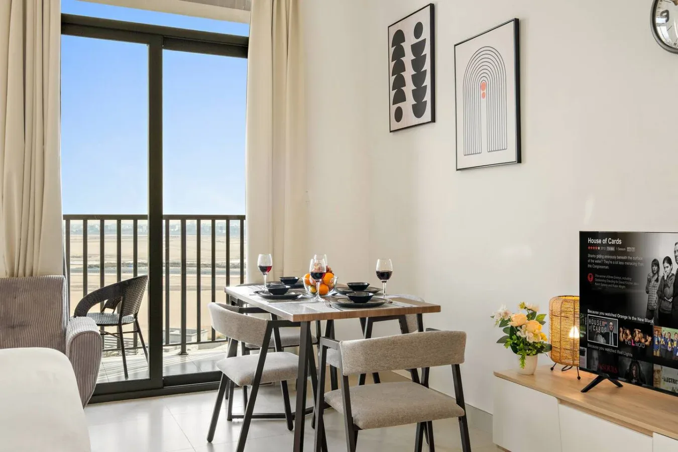 A dining area with a set table beside a glass door opening onto a balcony.