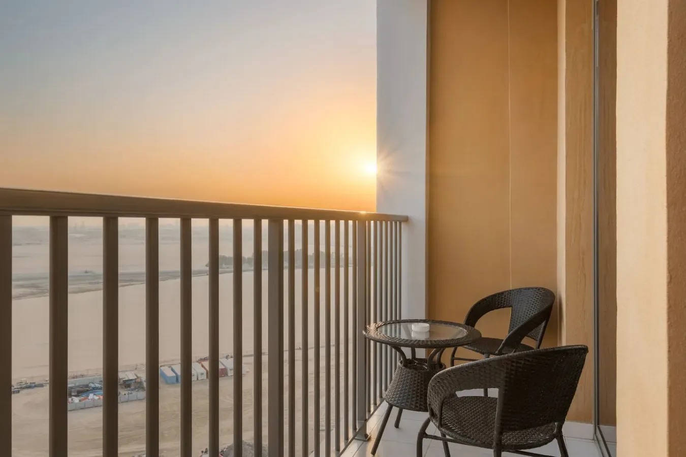 A balcony seating area overlooks the beach at sunset.